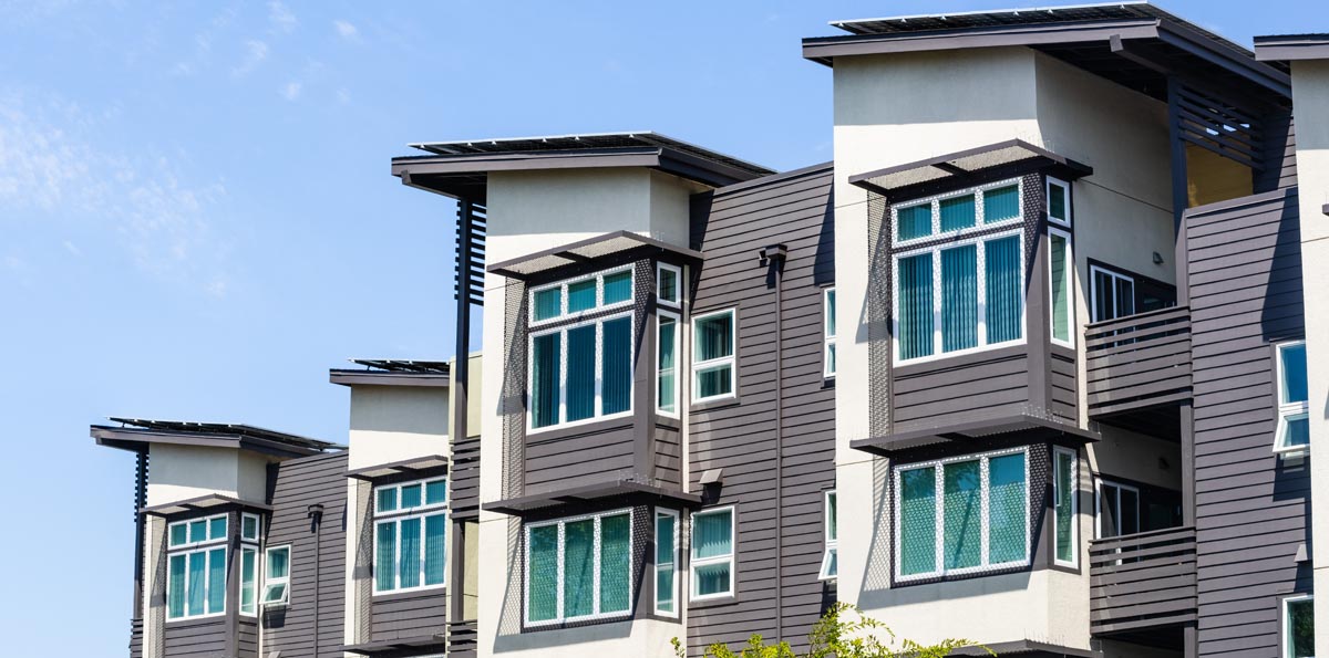 Townhomes with dark siding, white trim, and projecting bay windows.