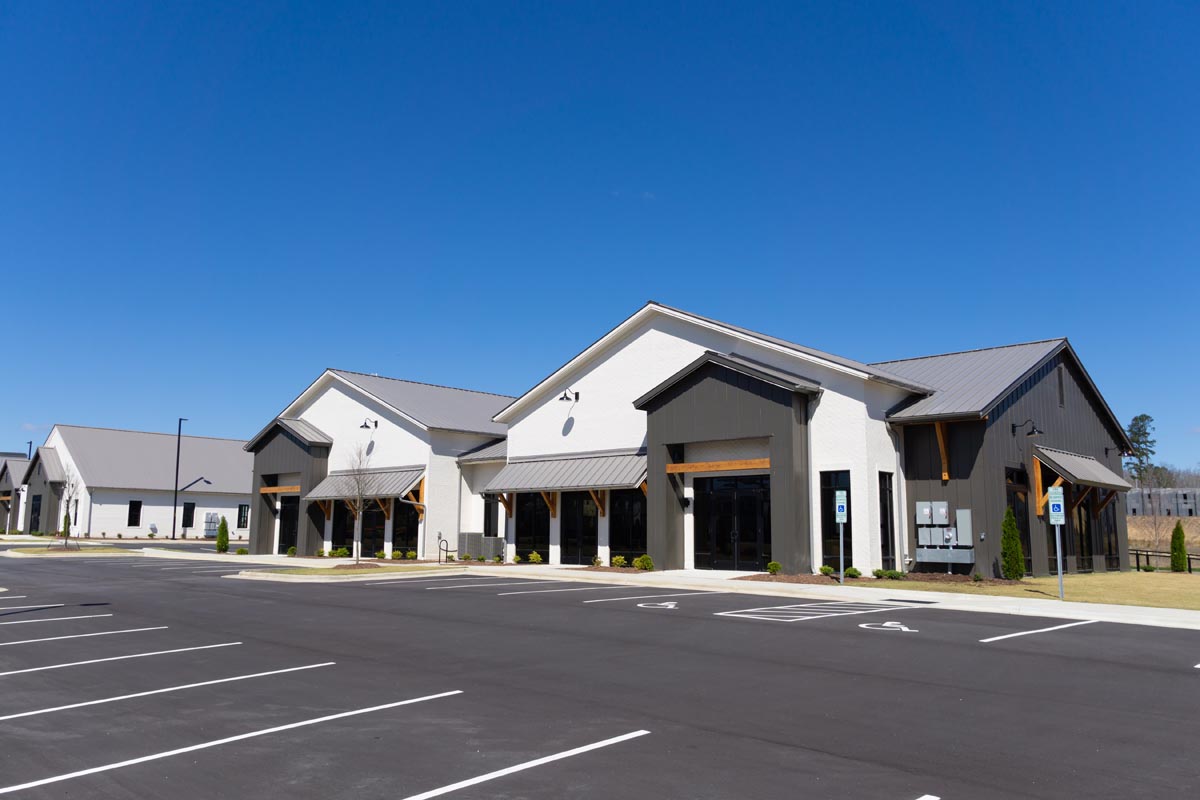 A row of new single-story shops with metal roofs and a parking lot.