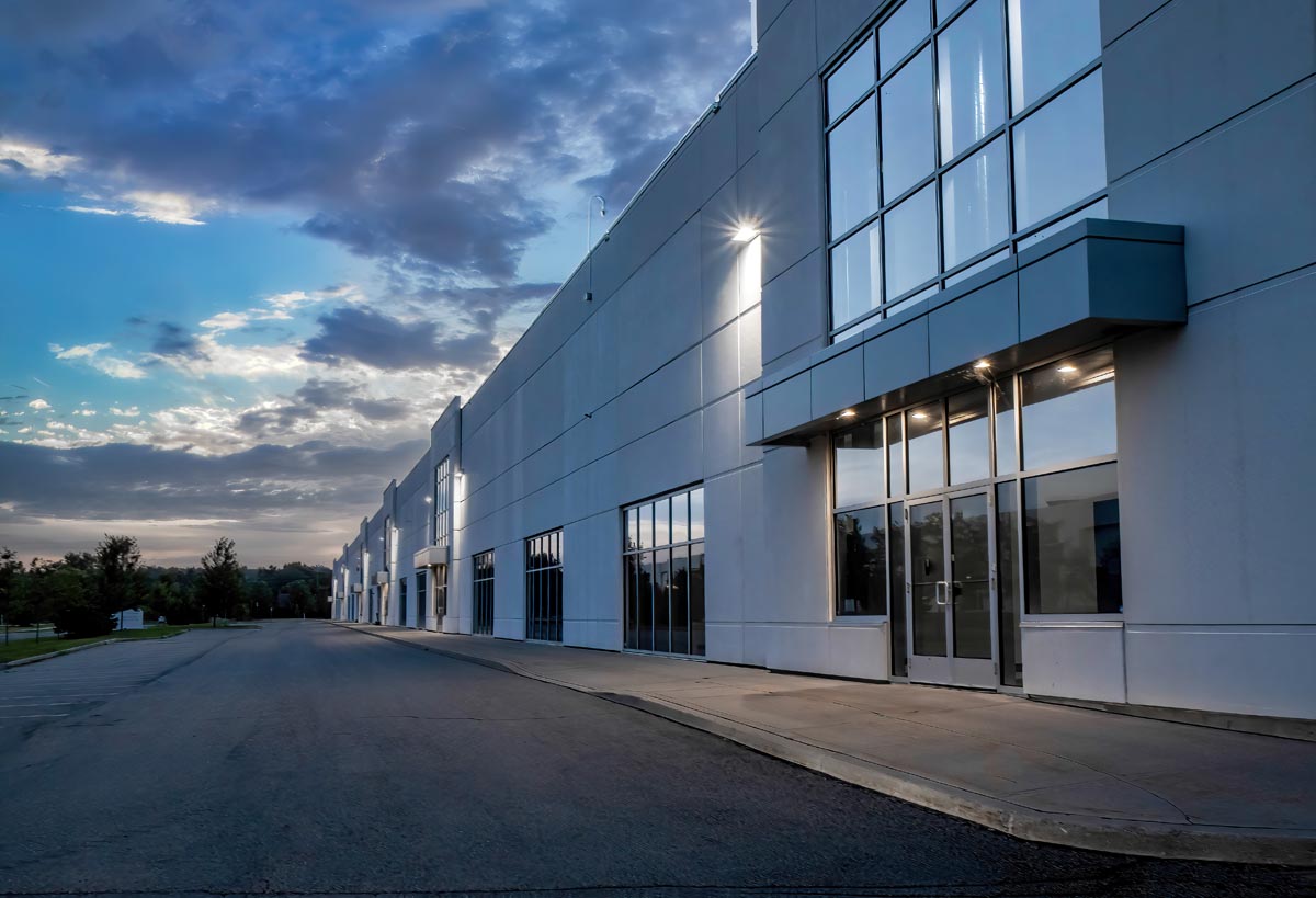 A long, low commercial building with a glass entry, photographed at dusk.