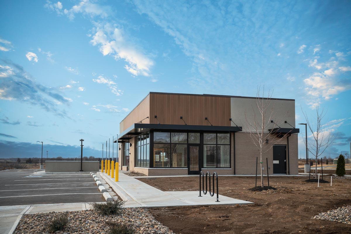A small single-story commercial building with wood panels, brick, and a glass storefront.