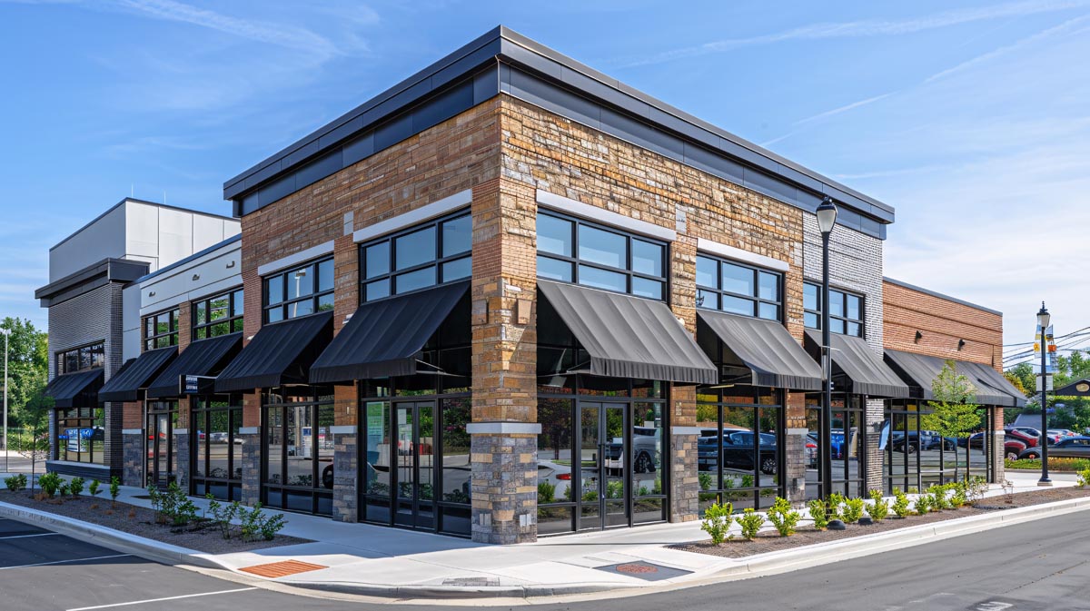 A corner retail building with stone columns, brick walls, and black awnings.
