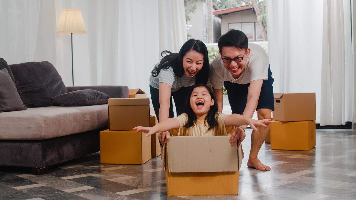 A family of three playing with cardboard boxes in a living room.