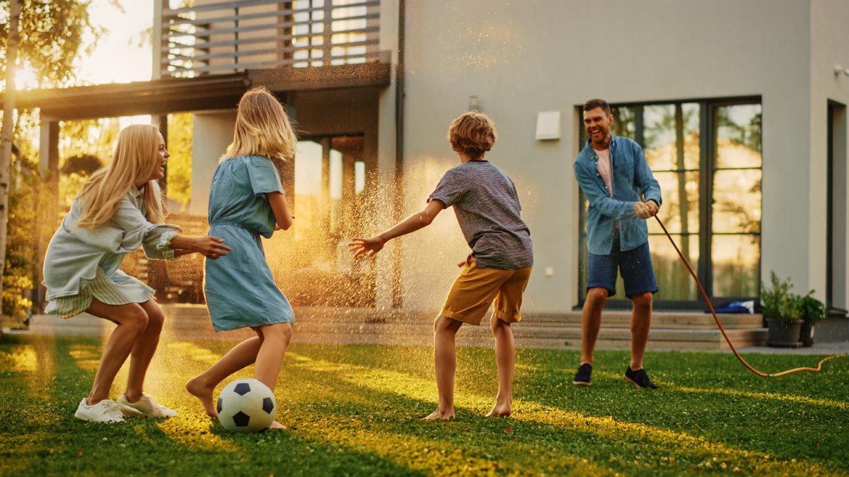 A family playing with a soccer ball and a hose on a lawn.