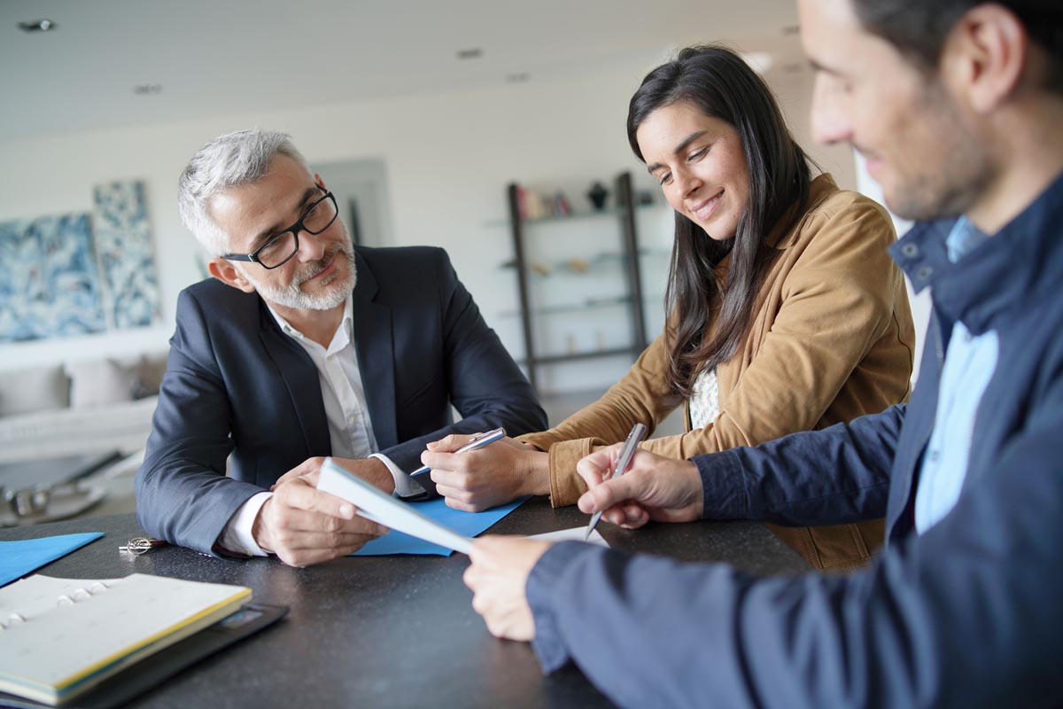 Three people reviewing papers together at a table.
